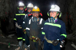 Mujer minera junto a colaboradores mineros dentro de mina subterránea